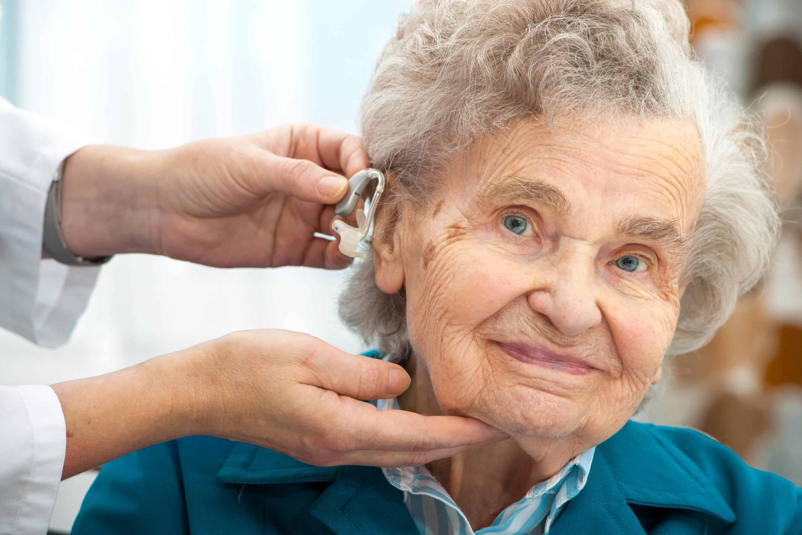 A doctor inserting a hearing aid on a senior A doctor inserting a hearing aid on a senior
