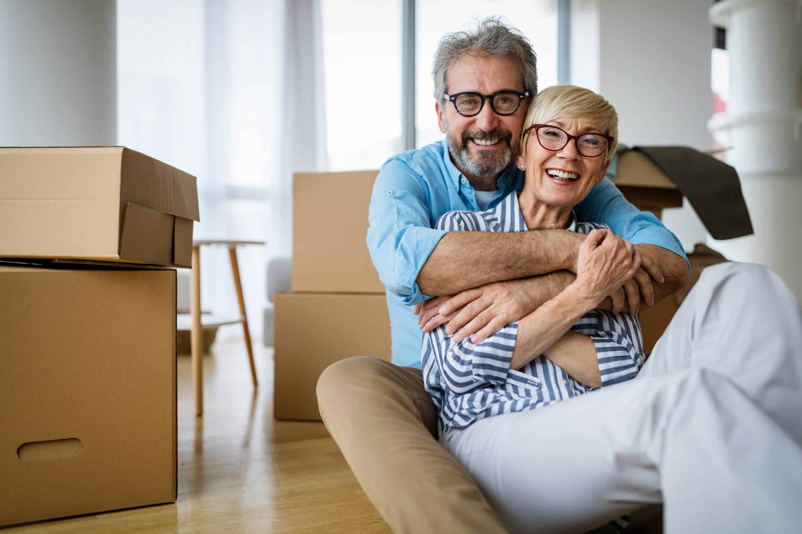 Man and woman sitting next to moving boxes Man and woman sitting next to moving boxes